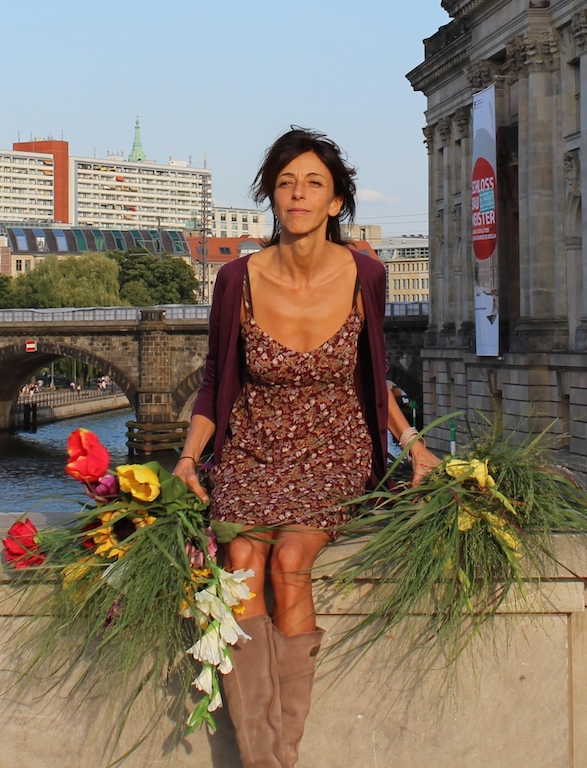 Gaby Haiber im Blumenkleid mit Blumensträußen auf der Mauer am Bodemuseum in Berlin
